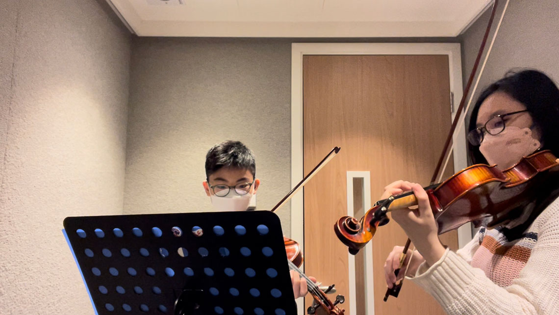 A photo of Jamie and a violin student both practicing in a room