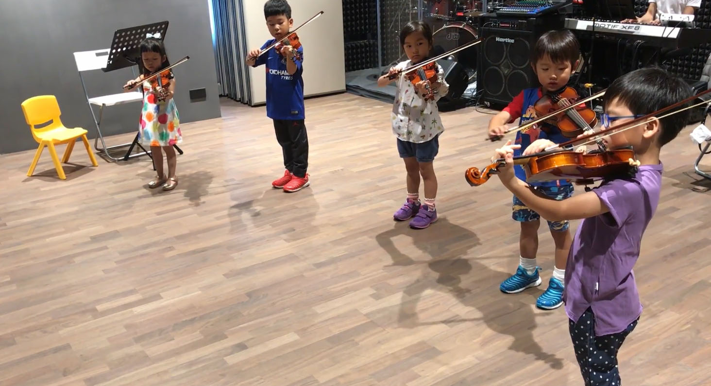 A group of boys and girls practicing the violin